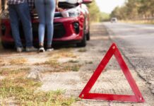 Rozładowany akumulator na trasie - trójkąt przy drodze i auto z podniesioną maską