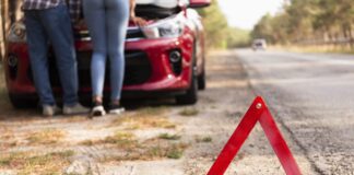 Rozładowany akumulator na trasie - trójkąt przy drodze i auto z podniesioną maską