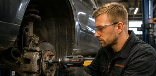 na zdjęciu mechanik przy odkręcaniu koła - narzędzia potrzebne do naprawy samochodu