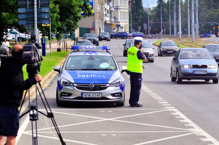 masowe kontrole drogowe na zdjęciu policjant mierzy prędkość radarem